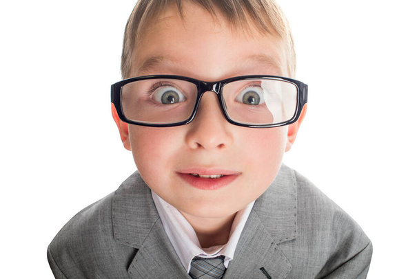 Gözlüklü komik bir çocuğun portresi ve beyaz bir arka planda takım elbise. Takım elbiseli ve gözlüklü akıllı çocuk büyük gözleriyle kameraya bakıyor.. - Fotoğraf, Görsel