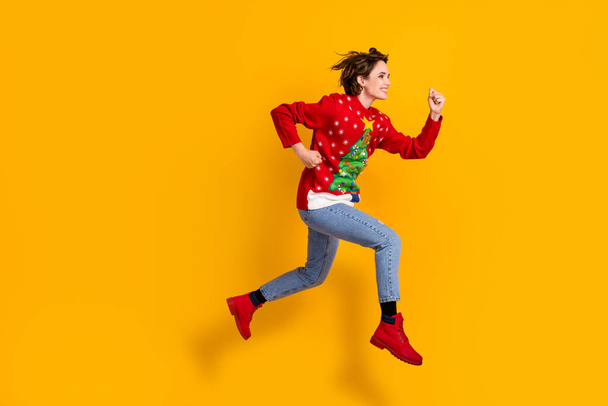 Повна довжина профілю бічна фотографія дівчини стрибок запустити Різдвяний час Ноель вечірка носити різдвяний ялинковий декор светр пуловер джинсові чоботи ізольовані яскравий блискучий кольоровий фон
 - Фото, зображення