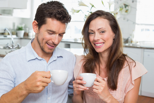 Happy young couple with coffee cups in kitchen - Photo, Image