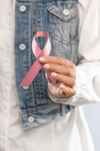 Koncepcja opieki zdrowotnej i medycyny - zbliżenie ręce kobiety trzymające różową wstążkę świadomości raka piersi. - Zdjęcie, obraz