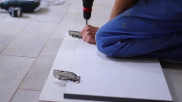 proces remontu mieszkania. fettler wierci gwoździe elektrycznym śrubokrętem w zawiasy drzwiowe na elewacji. nierozpoznawalnych mężczyzn. remonty, remonty. Nagrania w Full HD - Materiał filmowy, wideo