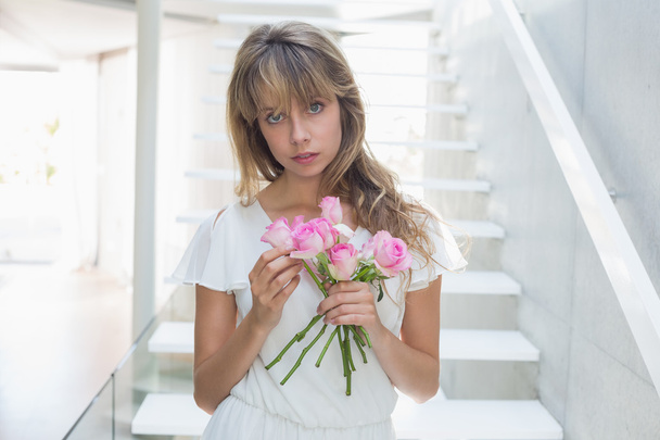 Portrait of a beautiful sad woman with flowers on stairs - Photo, Image