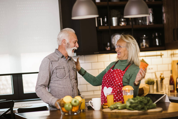 Старшая пара наслаждается во время подготовки обед вместе на кухне - Фото, изображение