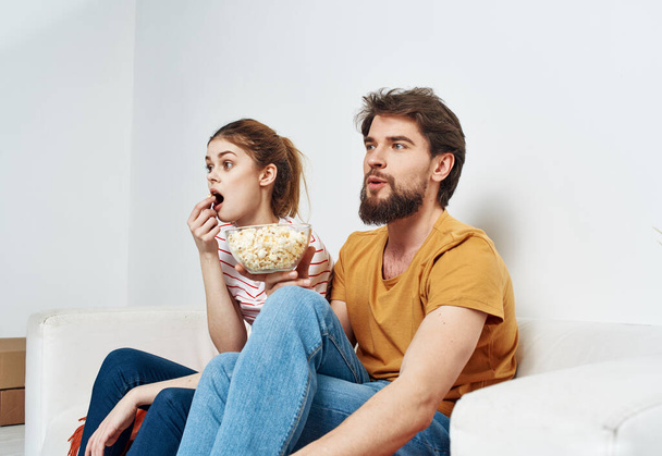 Hommes femmes avec popcorn dans une assiette à l'intérieur sur le canapé - Photo, image