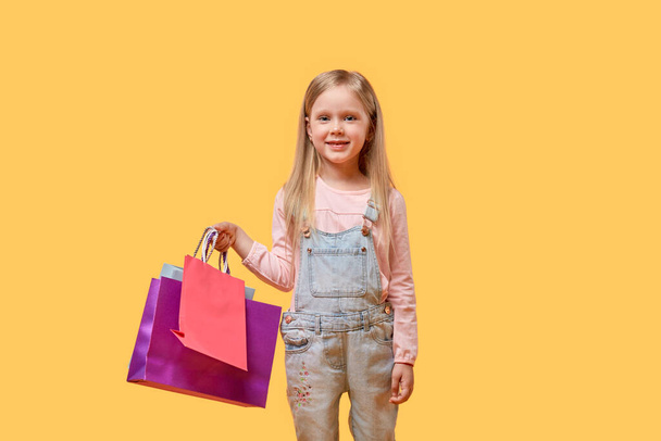 The girl smiles and holds shopping bags in her hands. Gifts for the holidays. - Фото, зображення