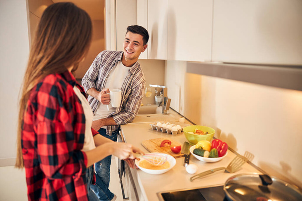 Muž se dívá na svou manželku, jak vaří snídani - Fotografie, Obrázek
