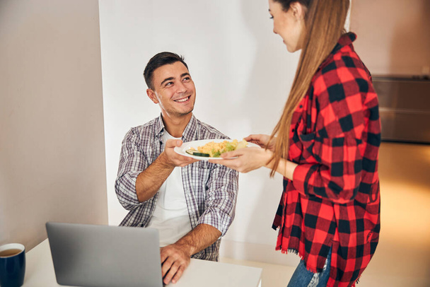 Housewife handing the omelet with a salad to her husband - Photo, image