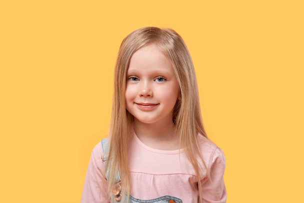 Little blonde girl looks at the camera and smiles. - Valokuva, kuva