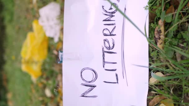 No littering sign in the park surrounded by plastic trash and polyethylene bags. Vertical 4k video. Climate change concept. Environment protection. Take care of planet  - Footage, Video