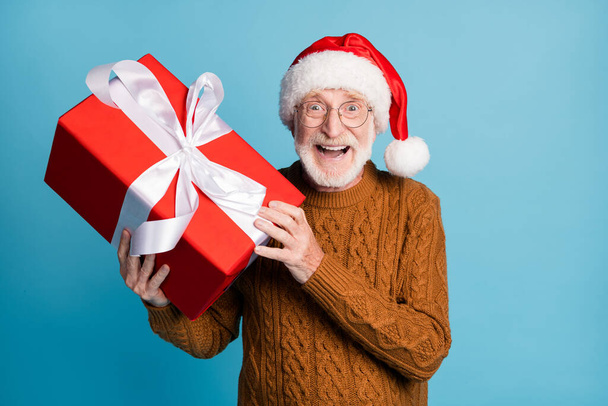 Portret van hem hij mooie aantrekkelijke vrolijke blij oudere bebaarde grijs-harige Santa vader houden in handen grote giftbox seizoen verkoop geïsoleerd over blauw pastel kleur achtergrond - Foto, afbeelding