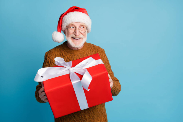 Portret van zijn hij mooie aantrekkelijke vrolijke soort bejaarde bebaarde grijs-harige Santa vader houden in handen kerst grote grote giftbox verkoop geïsoleerd over blauw pastel kleur achtergrond - Foto, afbeelding