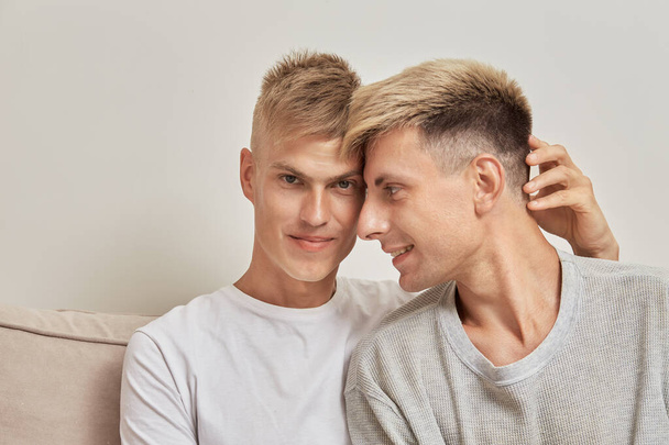 Portrait of two beautiful gay men sitting at home on the sofa. - Foto, Bild