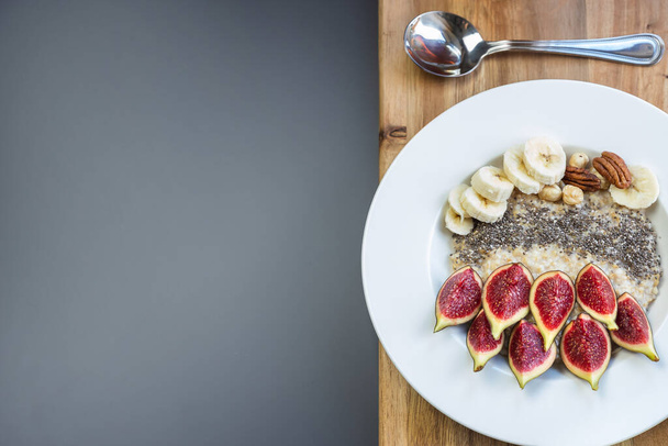 миска с овсяной кашей на завтрак с семенами чиа, свежей инжиром и бананом, выстрел сверху - Фото, изображение