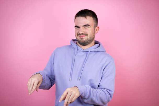 Young handsome man wearing casual sweatshirt over isolated pink background disgusted expression, displeased and fearful doing disgust face because aversion reaction. Annoying concept - Foto, afbeelding