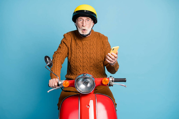 Portrait of his he nice attractive amazed stunned bearded grey-haired man riding moped using gadget pout lips social network post news reaction isolated over blue pastel color background - Photo, Image