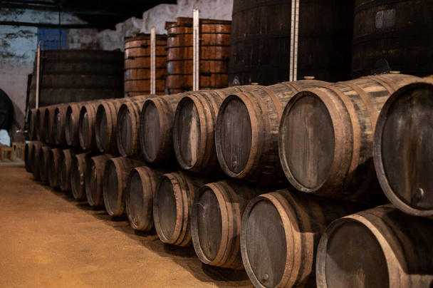 Old porto lodge with rows of oak wooden casks for slow aging of fortified ruby or tawny porto wine in Vila Nova de Gaia, north of Portugal - Photo, Image