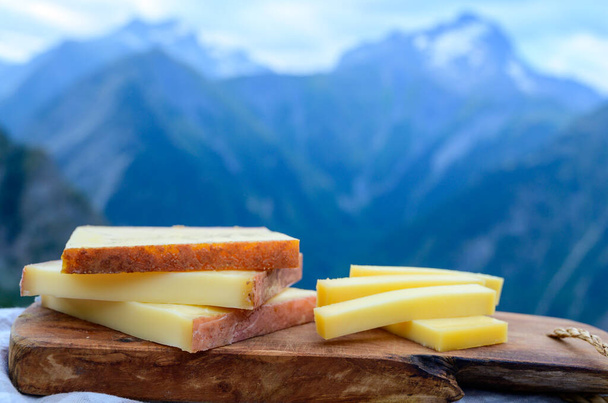Cheese collection, French comte, beaufort or abondance cow milk cheese served outdoor with Alps mountains peaks in summer on background - Photo, Image