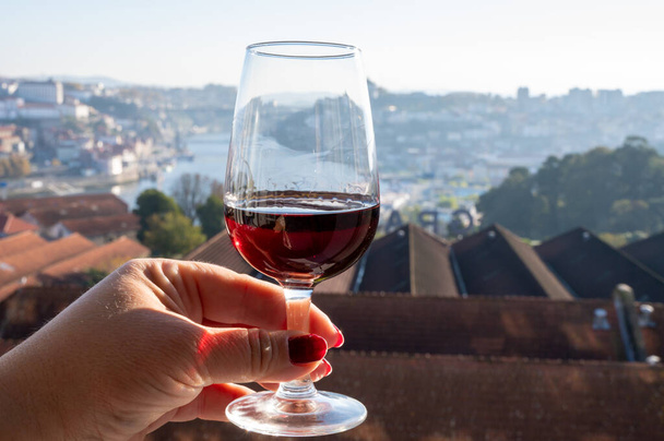 Tasting of different fortified dessert ruby, tawny port wines in glasses with view on Douro river, porto lodges of Vila Nova de Gaia and city of Porto, Portugal, close up - Photo, Image