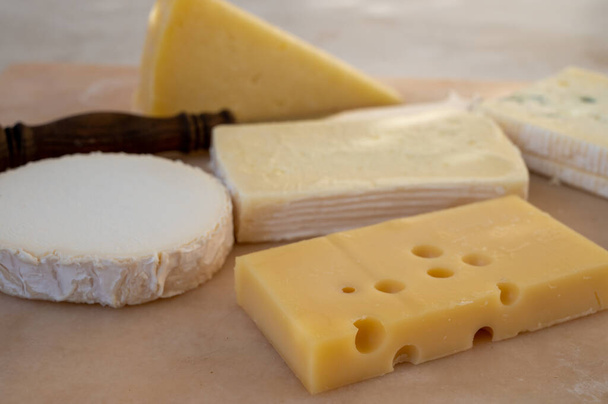 Ranskalainen juustokokoelma marmorilaudalla, emmental, carre de aurillac, petit cantal AOP Jeune, buche chevre ja brie - Valokuva, kuva