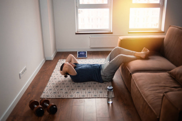 Hombre joven haciendo ejercicio en línea en casa - Foto, Imagen