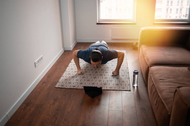 Hombre joven haciendo ejercicio en línea en casa - Foto, imagen
