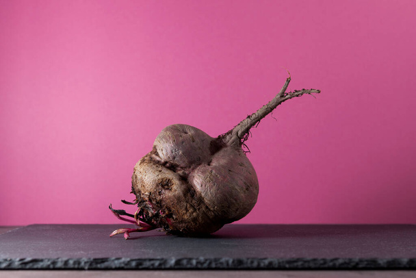 Ugly beetroot on a pink background, close-up. Vegetables of unusual shape, reduction of food organic waste. - Fotoğraf, Görsel