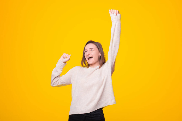 Photo of amazed young girl standing over yellow background celebrating victory fists up - Foto, Imagem