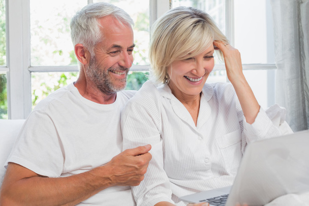 Happy mature couple using laptop in bed - Foto, immagini