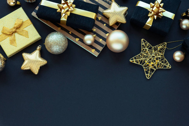 Újévi ajándékok fekete dobozokban és karácsonyi játékok fekete alapon. Felülnézet, lapos fekvés, másolás. - Fotó, kép