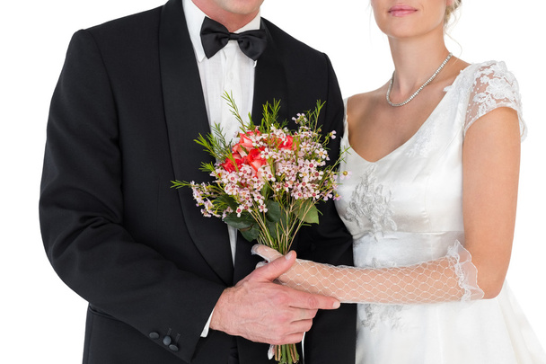 Mid section of bride and groom with flower bouquet - Фото, зображення