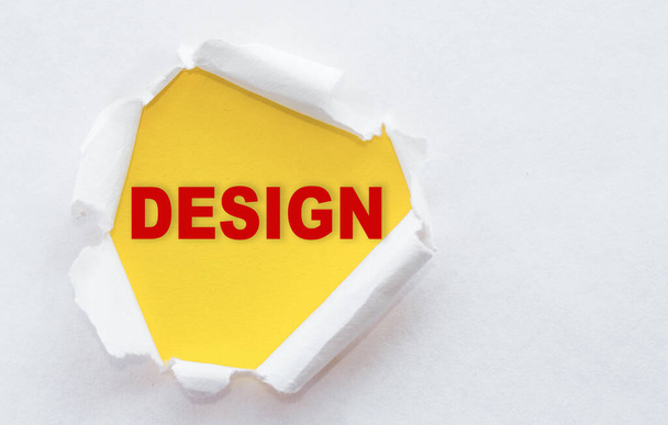 Top view of white torn paper and the text DESIGN on a yellow background - Фото, изображение