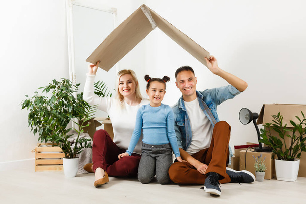 Счастливая семья с картонными коробками в новом доме в день переезда. - Фото, изображение