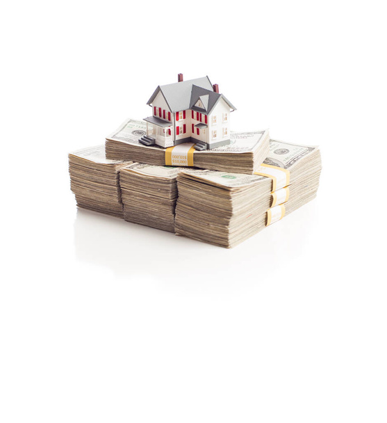 Klein huis op stapels van honderd dollar rekeningen geïsoleerd op een witte achtergrond. - Foto, afbeelding