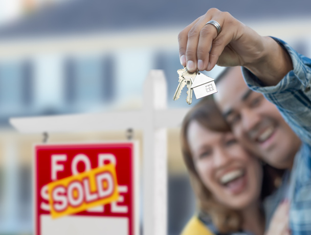 Couple mixte en face de Vendu Immobilier signe et maison avec clés. - Photo, image