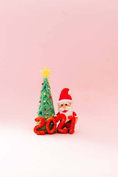 Playful clay christmas concept. Colorful handmade miniature Christmas tree and Santa Claus on pink background. 2021 new year. - Foto, Bild