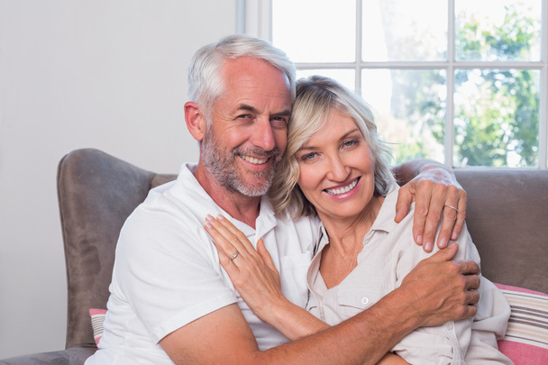 Mature man embracing woman on couch - Photo, Image
