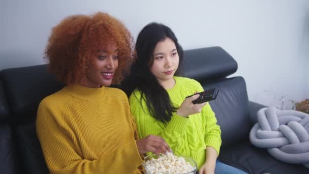 Amistad multirracial. Afican americano negro y asiático mujer comer palomitas de maíz y ver películas - Metraje, vídeo