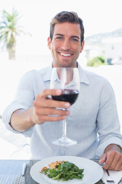 Улыбающийся молодой человек с бокалом вина за едой
 - Фото, изображение
