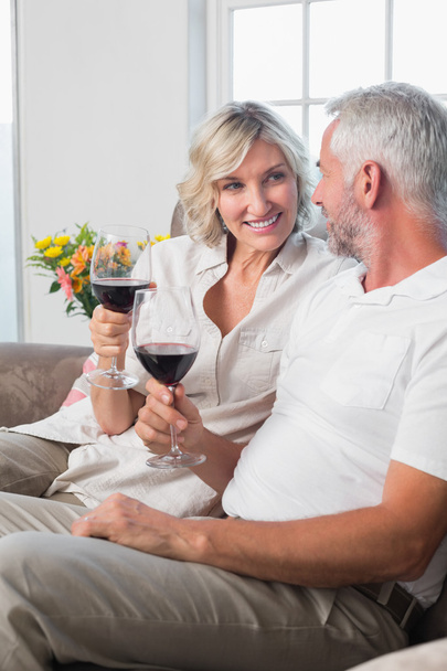 Happy mature couple with wine glasses in living room - Foto, Bild