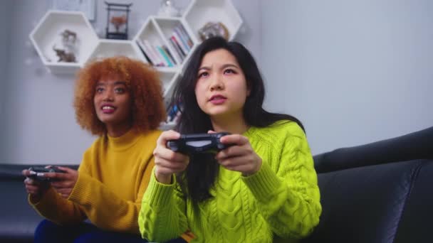 Lesbiennes couple lgbt femmes jouent à des jeux à la maison, les femmes asiatiques et afro-américaines ayant moment heureux drôle ensemble sur le canapé dans le salon dans la nuit. - Séquence, vidéo