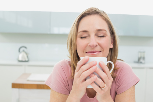 Primer plano de una mujer relajada tomando café en la cocina
 - Foto, imagen