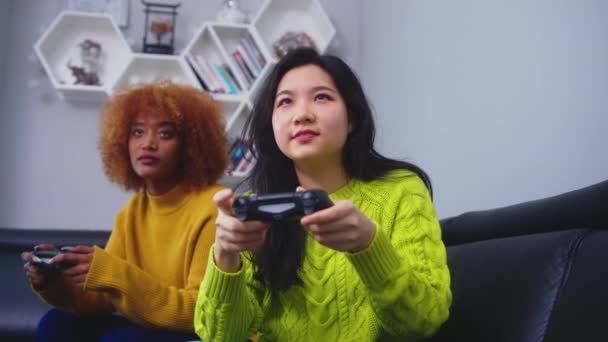 Lesbo lgbt naiset pari pelata pelejä kotona, Aasian ja Afrikan Amerikan naaraat ottaa hauska onnellinen hetki yhdessä sohvalla olohuoneessa yöllä. - Materiaali, video