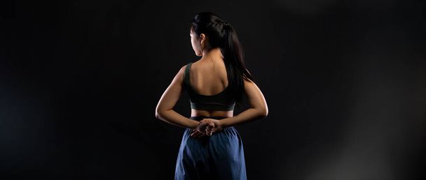Maestro Cinturón Negro TaeKwonDo Karate chica que es atleta nacional joven adolescente muestran tradicionales poses de lucha en el vestido deportivo, fondo negro espacio de copia aislado, vista trasera - Foto, Imagen