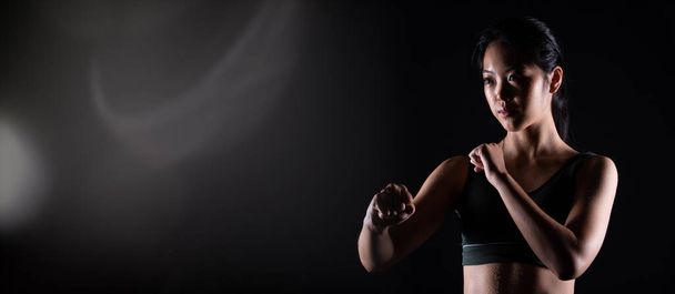 Genç sporcu olan Siyah Kemer Tekvando Karate Kız geleneksel dövüş pozlarını spor elbisesi, siyah arka plan izole, fotokopi alanı düşük karanlık pozlar - Fotoğraf, Görsel