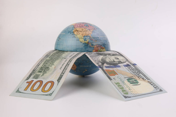 Americký dolar měna papírové peníze 100 dolarů bankovka přes planetu zeměkoule na bílém pozadí - Fotografie, Obrázek