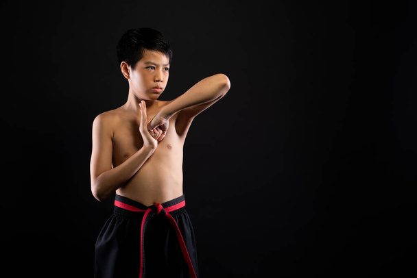 Master Red Black Belt TaeKwonDo Karaté garçon qui est athlète jeune adolescent montrer traditionnelle pose de combat dans la robe de sport, fond noir espace de copie isolé - Photo, image