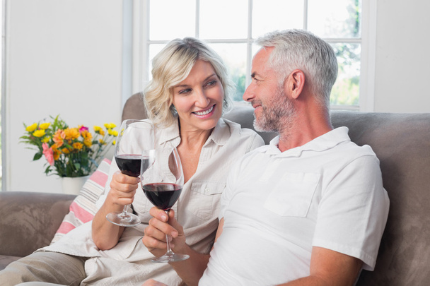 Happy loving mature couple with wine glasses in living room - Foto, Imagen