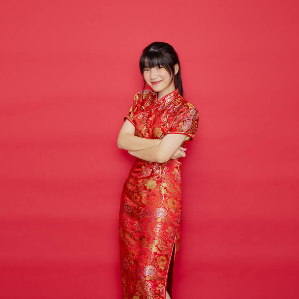 Nette junge Asiatin trägt Cheongsam mit Aktion zum chinesischen Neujahrskonzept auf rotem Hintergrund - Foto, Bild