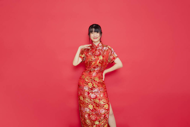 Aranyos fiatal ázsiai nő visel cheongsam cselekvési kínai újév koncepció piros alapon - Fotó, kép