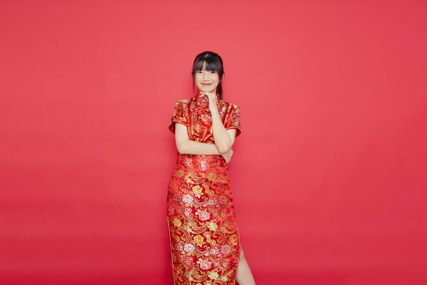 Cute young Asian woman wear cheongsam with action for Chinese new year concept on a red background - Photo, Image